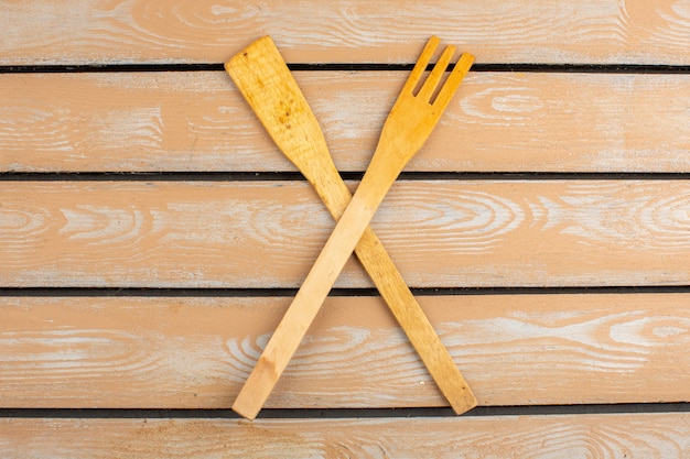 Crossed kitchen tools wooden made on a bright background