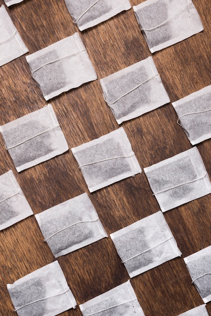 Free photo crossed white tea bag on wooden textured backdrop