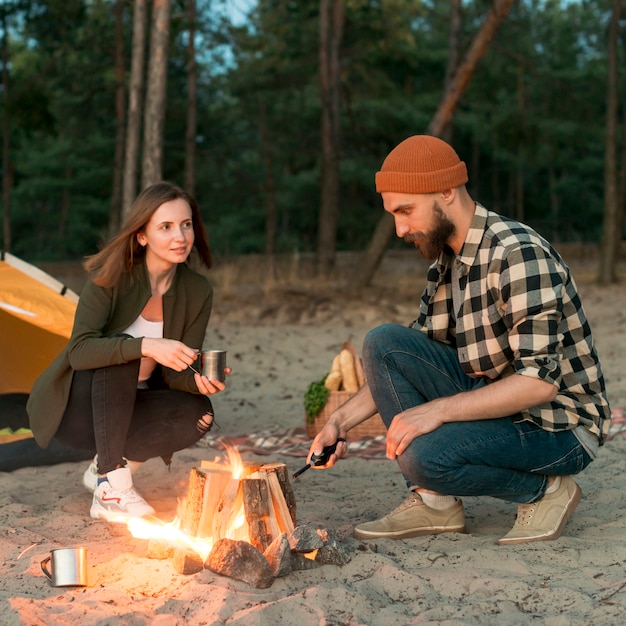 Crouching couple igniting bonfire