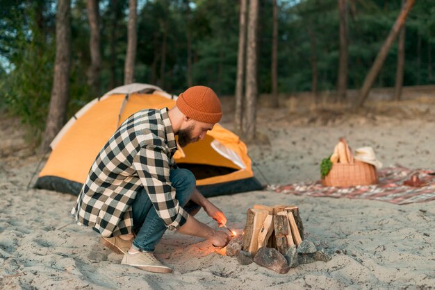 Crouching man igniting campfire