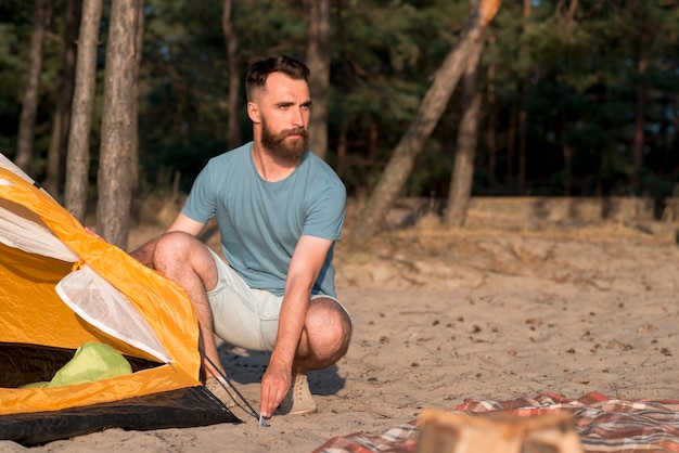 Crouching man setting up the tent 