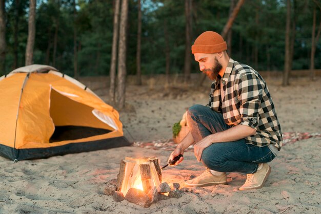 Crouching man starting a bonfire