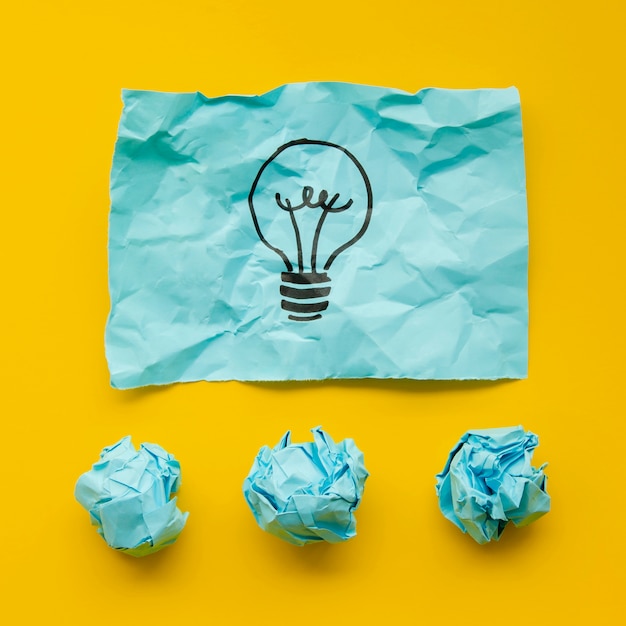 Free photo crumpled blue paper with light bulb in marker