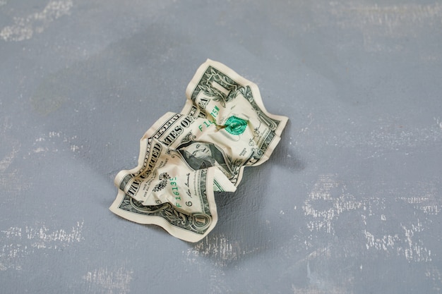 crumpled dollar banknote on plaster table .