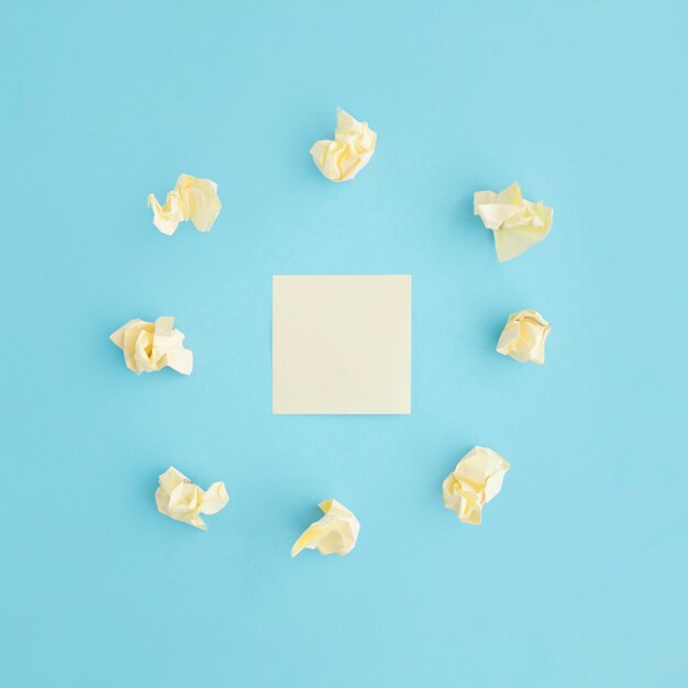 Crumpled paper surrounded around the blank sticky note over blue background