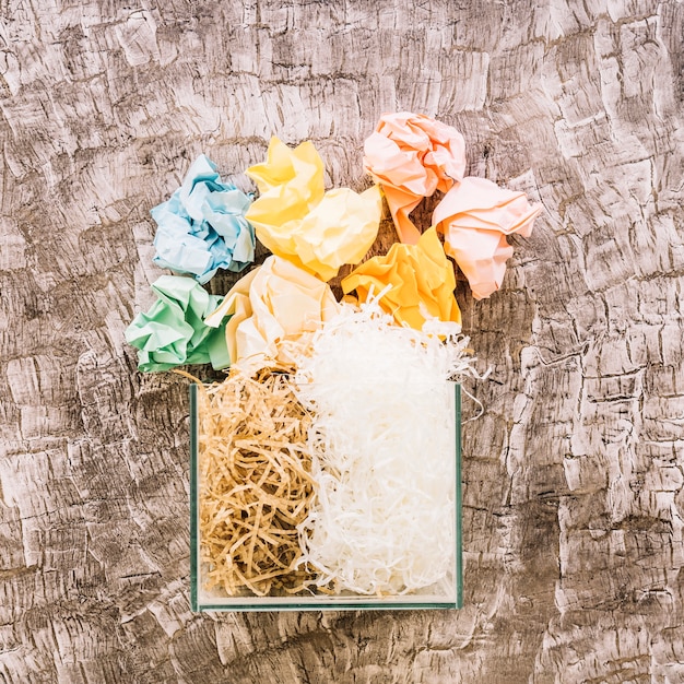 Crumpled papers over glass container filled with woodshave and plasticshave