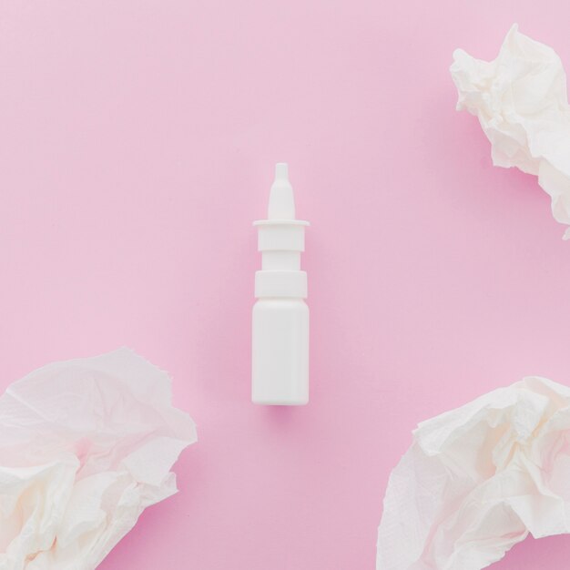 Crumpled white paper and dropper bottle on pink background