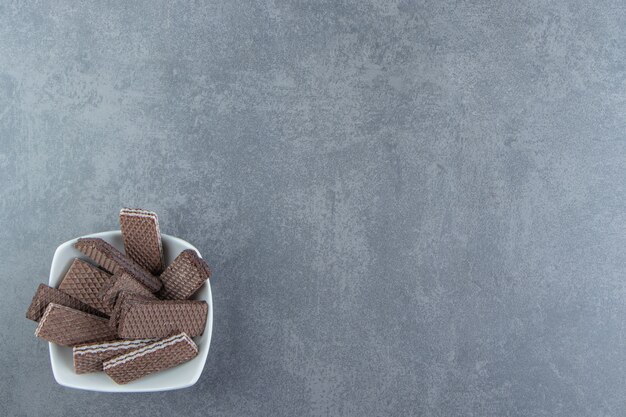 Crunchy chocolate waffles in white bowl. 