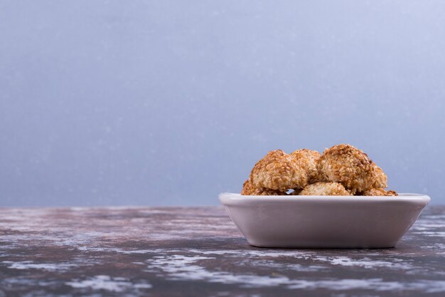 Crunchy cookies in a white ceramic saucer on blue.