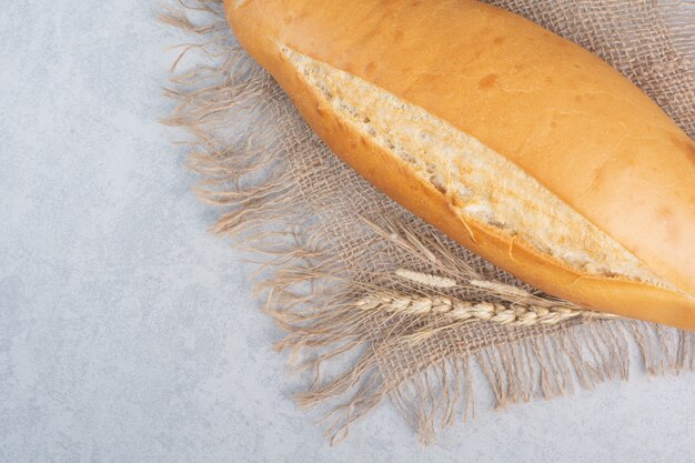 Crunchy loaf bread on burlap with wheat