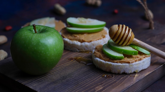Crunchy natural peanut butter sandwich with rice cake bread and green apple slices and honey. 