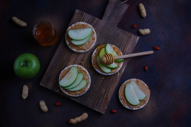 Crunchy natural peanut butter sandwich with rice cake bread and green apple slices and honey. 