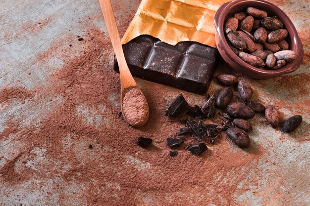 Разбитый сломанный шоколад и какао-бобовая чаша на деревенском фоне