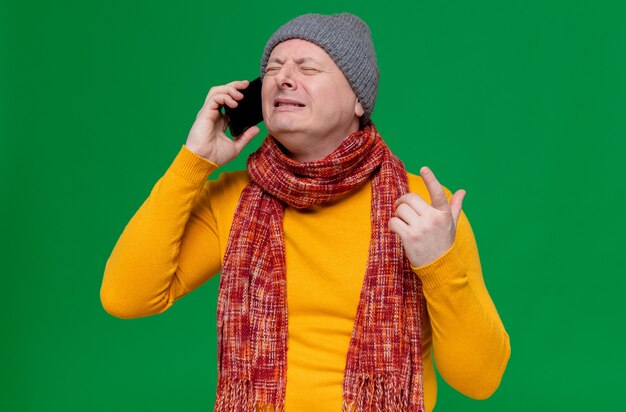 Crying adult slavic man with winter hat and scarf around his neck talking on phone 