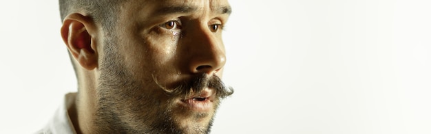 Crying. caucasian young man's close up cropped shot on studio wall. copyspace.