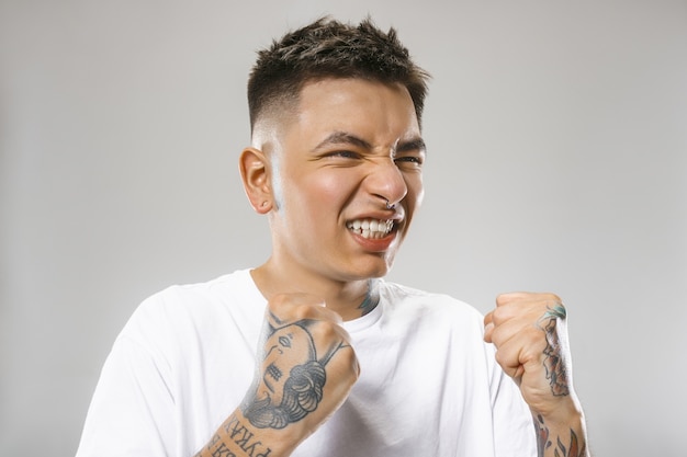 Free photo crying emotional angry man screaming on gray studio background. emotional, young face. male half-length portrait. human emotions, facial expression concept.