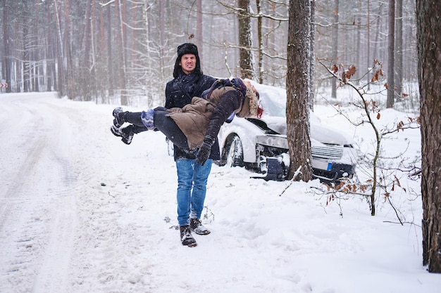 Foto gratuita l'uomo piangente sta trattenendo la donna ferita dopo un incidente d'auto e cerca aiuto.