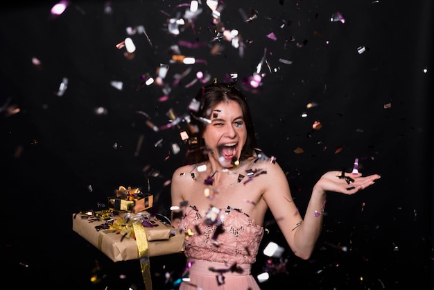 Crying woman with present boxes between confetti