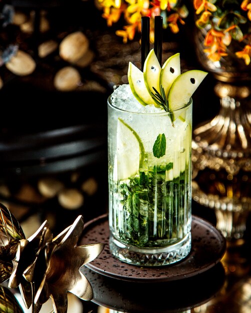 A crystal glass of mojito drink garnished with green apple slices