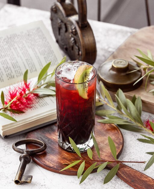 crystal glass of red cocktail garnished with kiwifruit slice