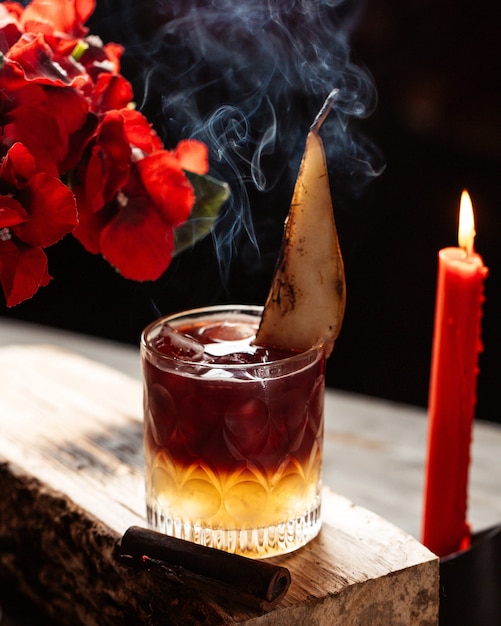 A crystal glass of two-layered cocktail garnished with pear slice