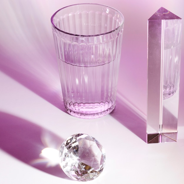 Хрустальное стекло воды; призма и блестящий бриллиант на розовом фоне