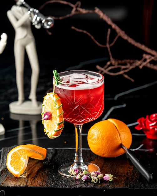 crystal glass with red cocktail garnished with orange wheel