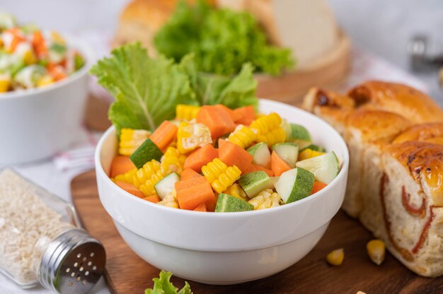 Салат из огурцов, кукуруза, морковь и салат в белой чашке.