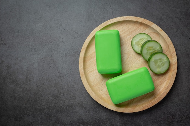 Cucumber slices and soap on dark background