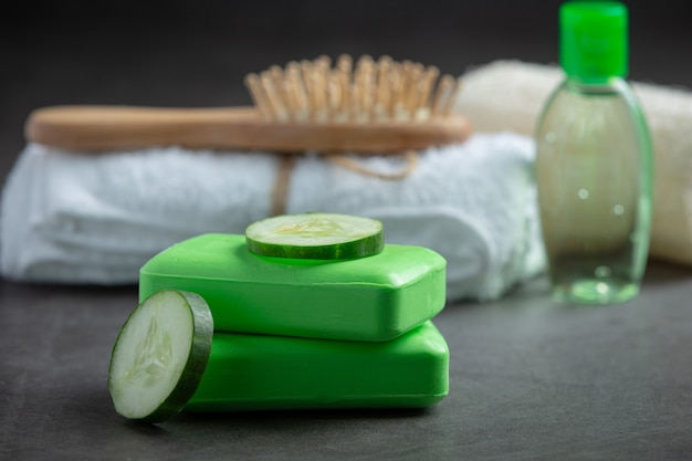 Cucumber slices and soap on dark background