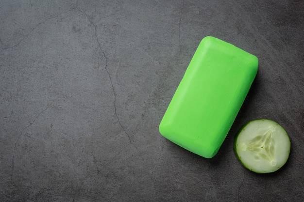 Cucumber slices and soap on dark background