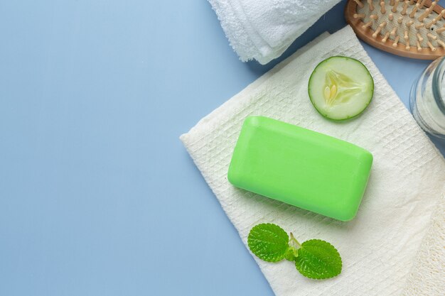 Cucumber slices and soap on light blue background