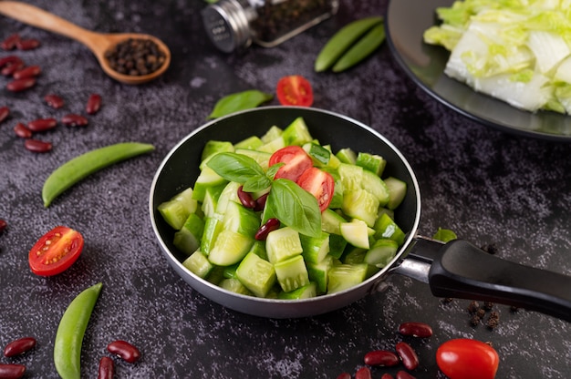 Cucumber stir-fried with tomatoes and red beans in a frying pan.