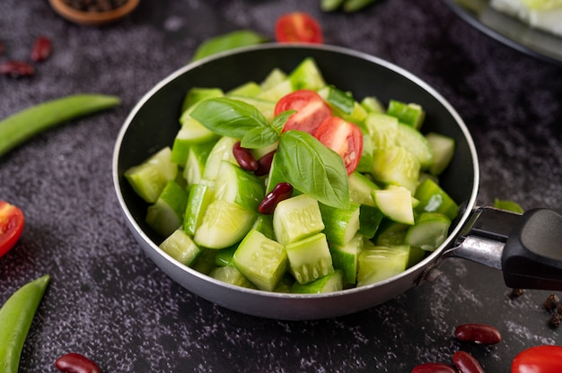 Free photo cucumber stir-fried with tomatoes and red beans in a frying pan.