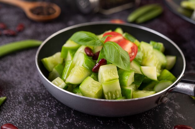 Free photo cucumber stir-fried with tomatoes and red beans in a frying pan.