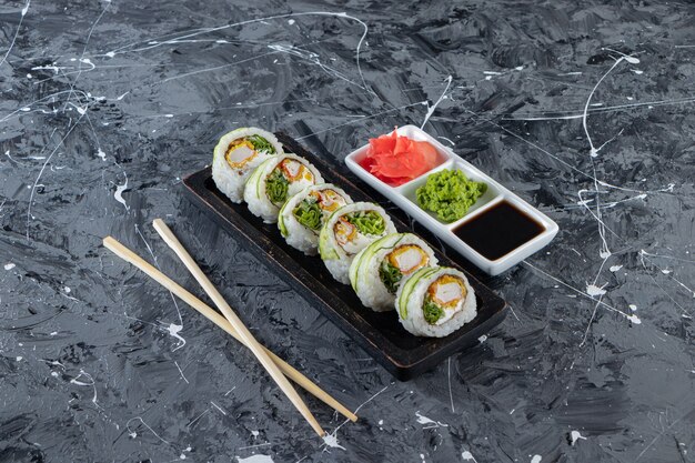 Cucumber sushi rolls with crab sticks on black plate.