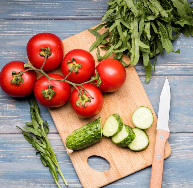 Cucumber and tomatoes on cutting board