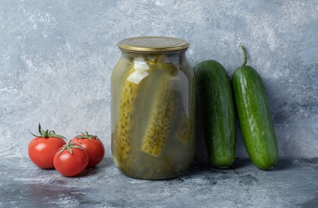 Free photo cucumbers pickled in a glass jar on a marble background.