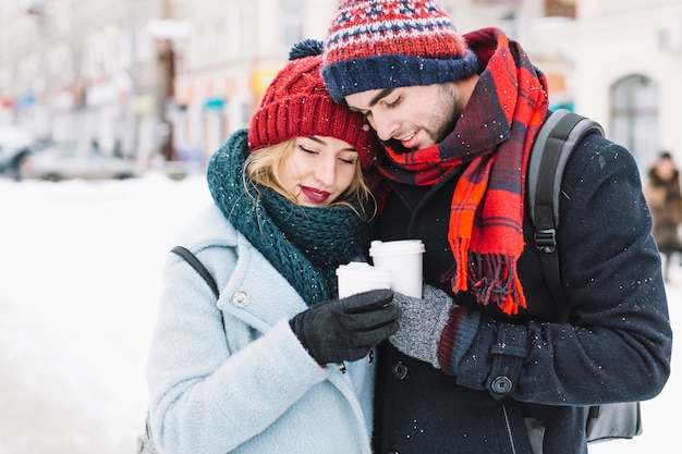 Cuddling couple having warming tea in winter