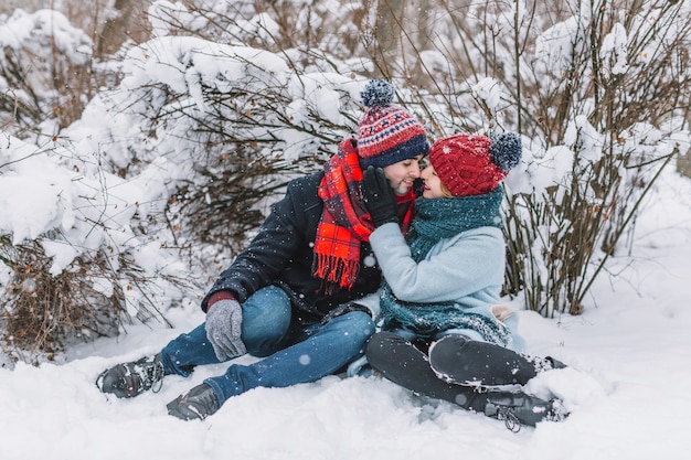 Cuddling loving couple sitting on snow
