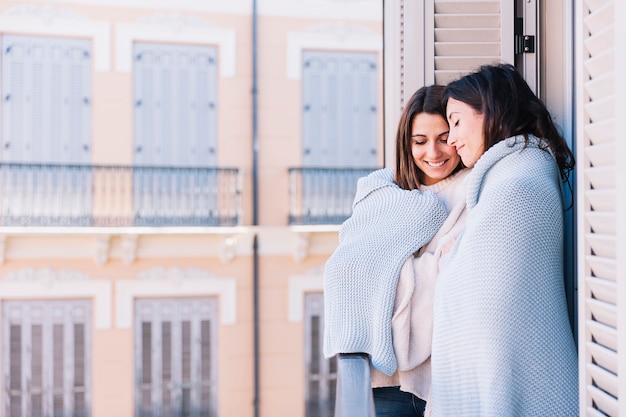 Cuddling women in plaid on terrace