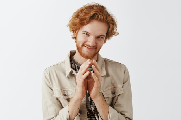 Cunning bearded redhead guy posing against the white wall