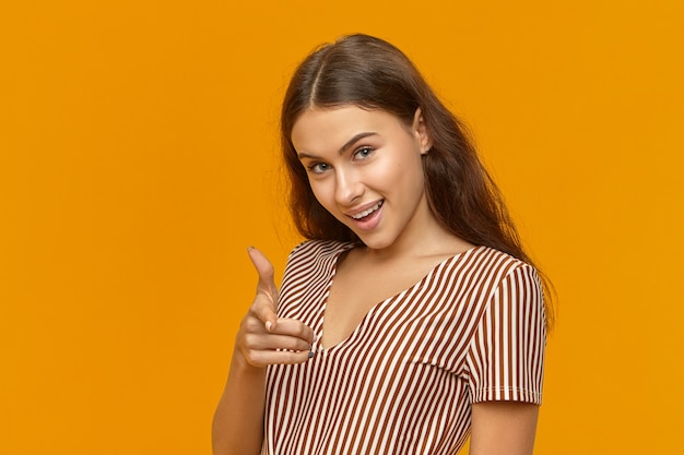 Cunning gorgeous young Caucasian woman dressed in striped top looking at camera