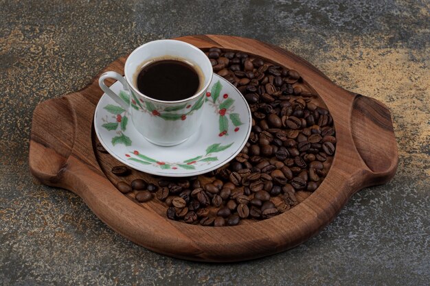 Cup of aroma espresso with coffee beans on wooden board. 