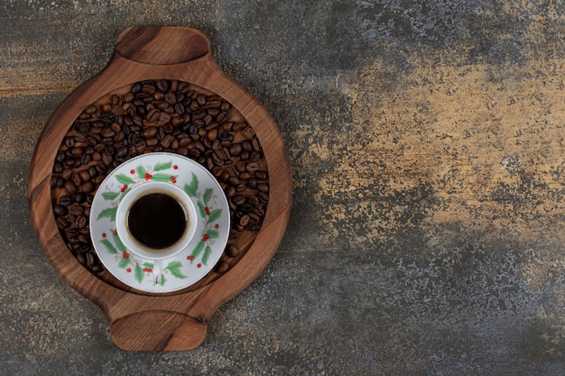 Cup of aroma espresso with coffee beans on wooden board. 