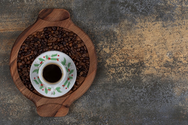 Чашка ароматного эспрессо с кофейными зернами на деревянной доске.