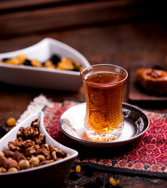 Cup of aromatic tea and bowl with nuts
