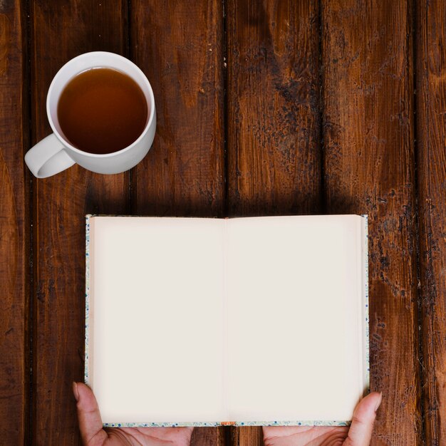 Cup of aromatic tea and open book on old wood