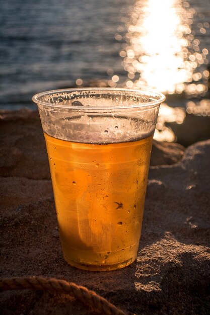 Cup of beer on the background of the ocean during the sunset