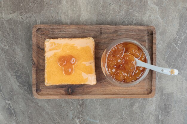 Cup of berry jam with spoon and toast bread on wooden plate. High quality photo